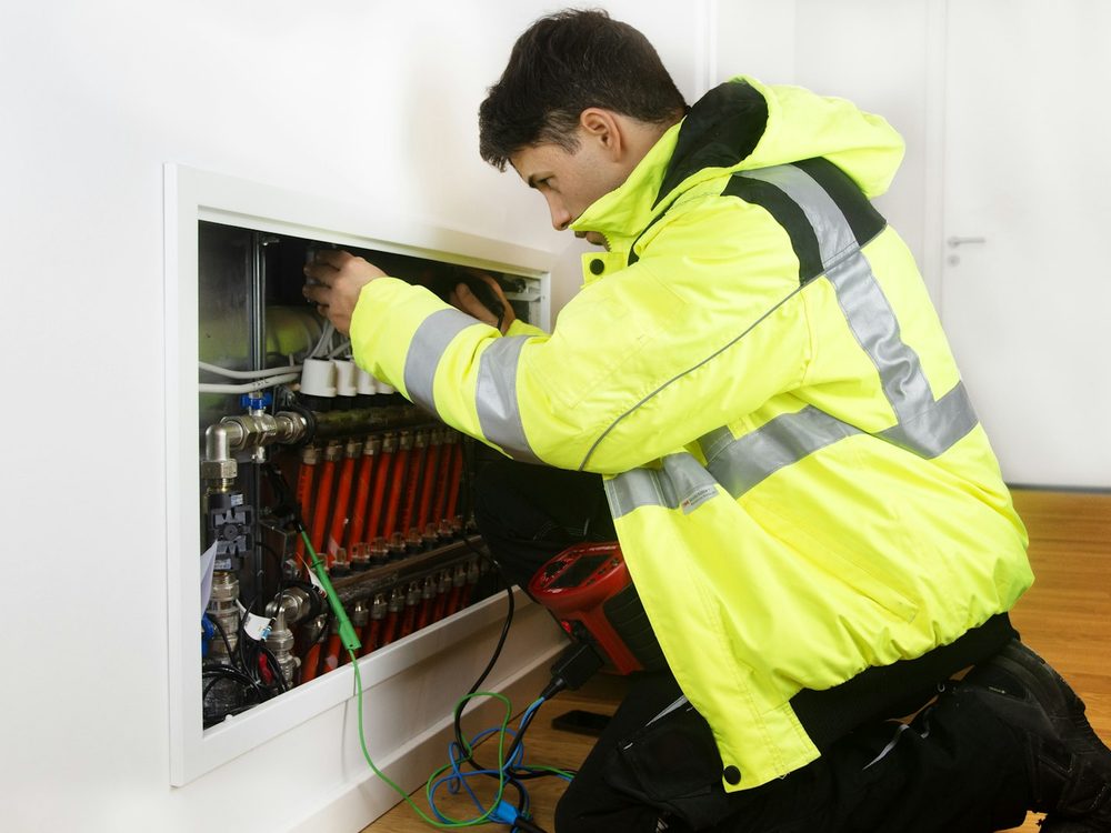 Engineer in a hi-vis jacket checking a heating distribution manifold